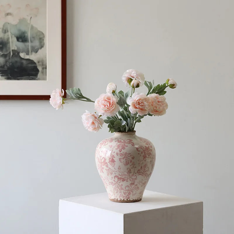 Decorative vase with floral arrangement on a white surface against a light gray wall.