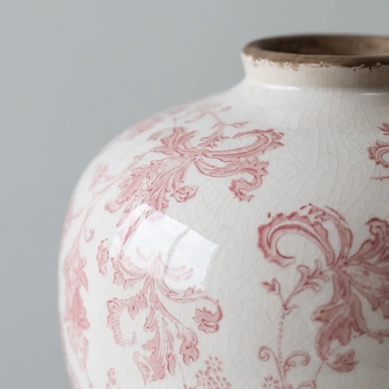 White ceramic vase with red floral patterns on a gray background